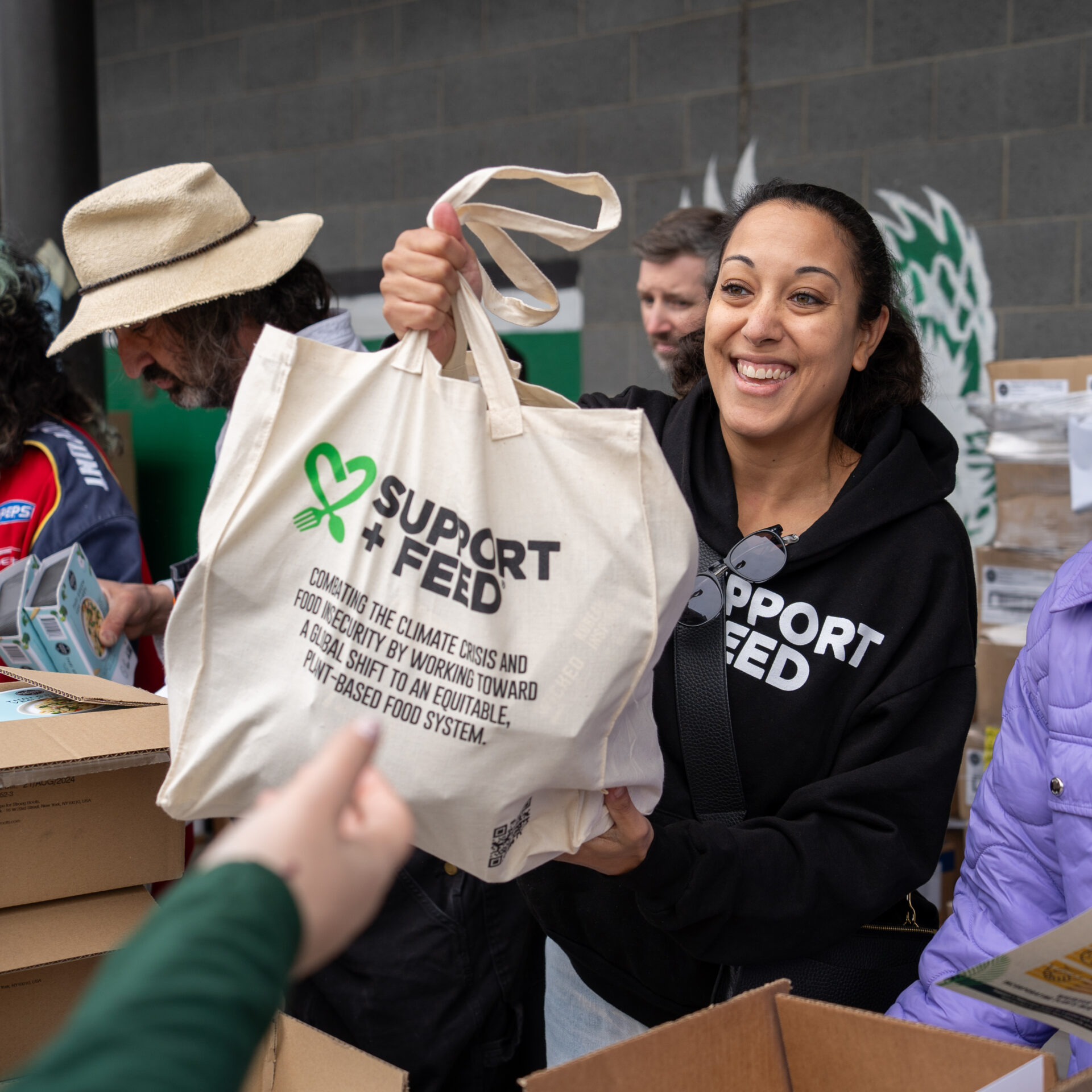 SUPPORT + FEED volunteer holding a food distribution bag
